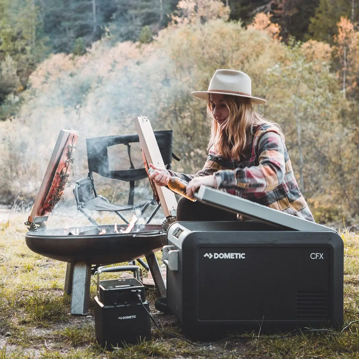 Mujer haciendo una barbacoa en el campo con nevera Dometic